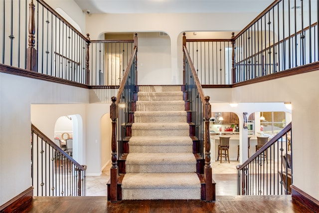 staircase with hardwood / wood-style floors and a towering ceiling