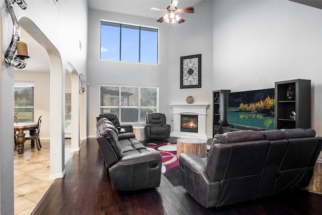 living room with ceiling fan, tile patterned flooring, and a towering ceiling