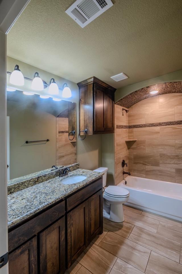 full bathroom featuring vanity, a textured ceiling, toilet, and tiled shower / bath