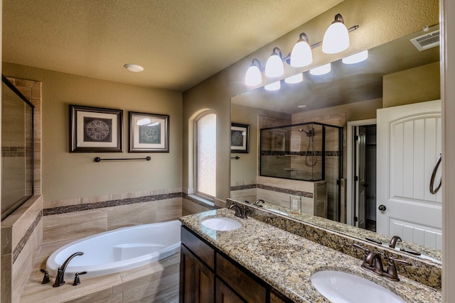 bathroom featuring vanity, a textured ceiling, and plus walk in shower