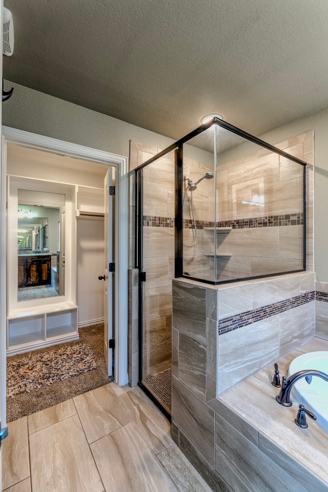 bathroom with a textured ceiling and separate shower and tub