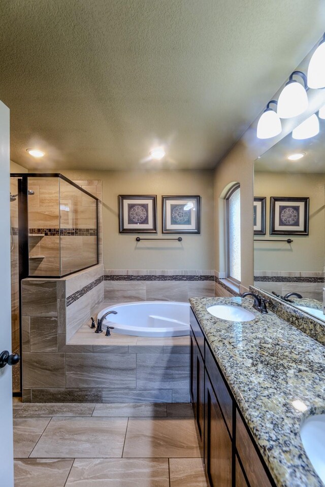 bathroom featuring independent shower and bath, vanity, and a textured ceiling