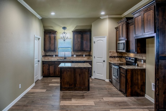 kitchen featuring a kitchen island, appliances with stainless steel finishes, dark brown cabinets, light stone countertops, and sink