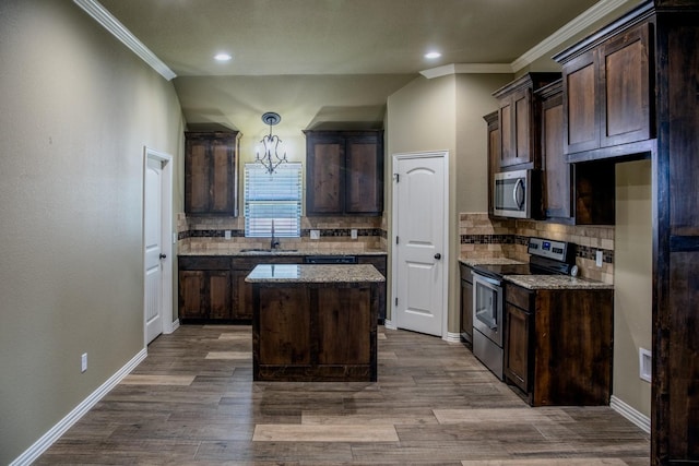 kitchen with appliances with stainless steel finishes, sink, a center island, light stone countertops, and dark brown cabinets