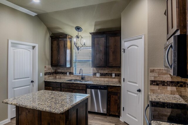 kitchen with appliances with stainless steel finishes, sink, a center island, and backsplash