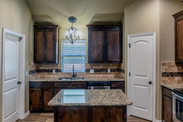 kitchen with sink, appliances with stainless steel finishes, light stone counters, hardwood / wood-style floors, and a center island