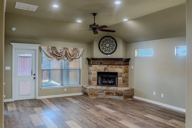 unfurnished living room featuring a wealth of natural light, a stone fireplace, light hardwood / wood-style floors, and vaulted ceiling