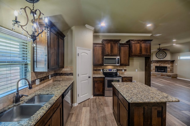 kitchen with stainless steel appliances, light hardwood / wood-style floors, decorative backsplash, sink, and a kitchen island