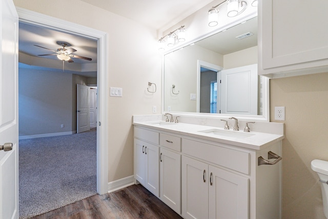 bathroom featuring toilet, vanity, hardwood / wood-style floors, and ceiling fan