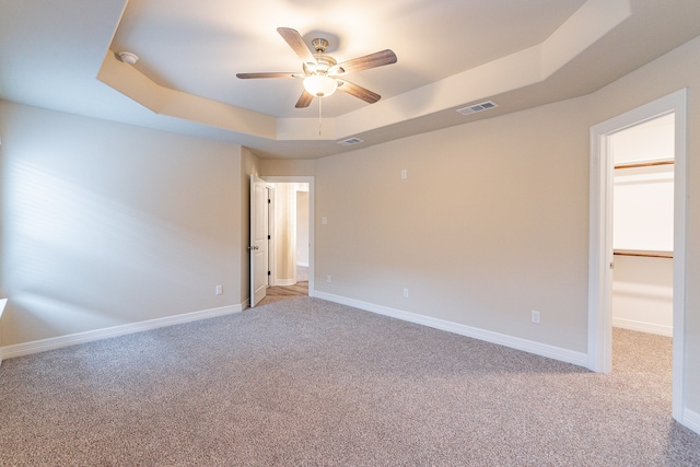 spare room featuring ceiling fan, light colored carpet, and a tray ceiling