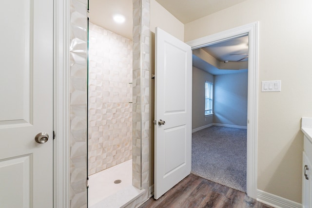 bathroom with wood-type flooring and a tile shower