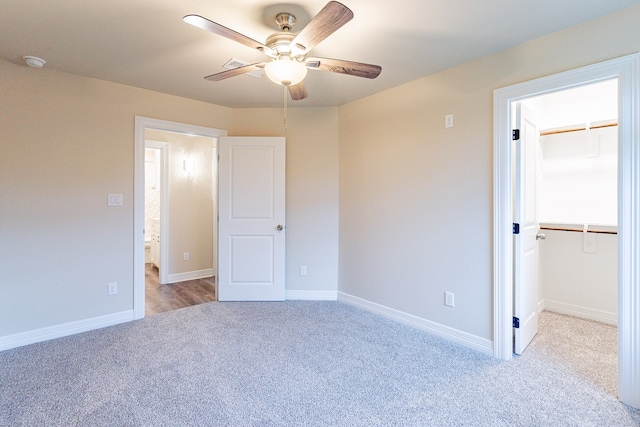 unfurnished bedroom featuring ceiling fan, a closet, a spacious closet, and light colored carpet