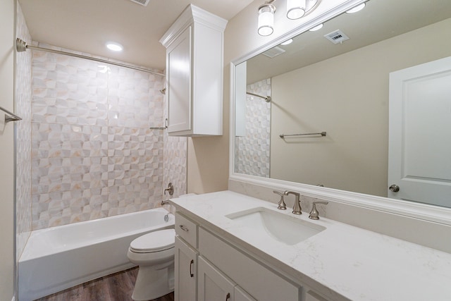 full bathroom featuring tiled shower / bath combo, vanity, hardwood / wood-style flooring, and toilet