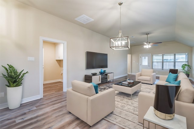 living room featuring light wood-type flooring, ceiling fan with notable chandelier, and lofted ceiling