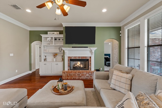 living room with hardwood / wood-style floors, ceiling fan, a fireplace, and ornamental molding