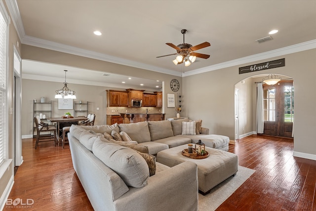 living room with dark hardwood / wood-style flooring, ceiling fan with notable chandelier, and crown molding