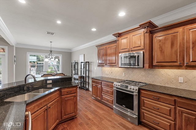 kitchen with light hardwood / wood-style floors, a notable chandelier, crown molding, appliances with stainless steel finishes, and dark stone countertops