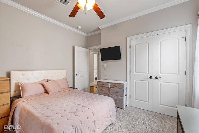 bedroom with a closet, light colored carpet, ceiling fan, and crown molding