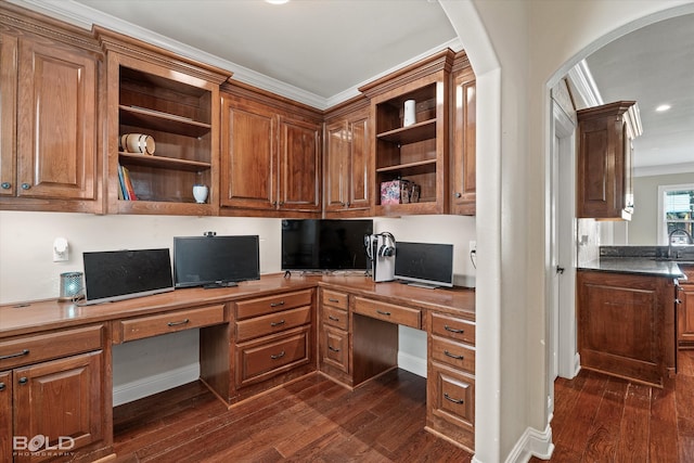 office featuring dark wood-type flooring, built in desk, and ornamental molding