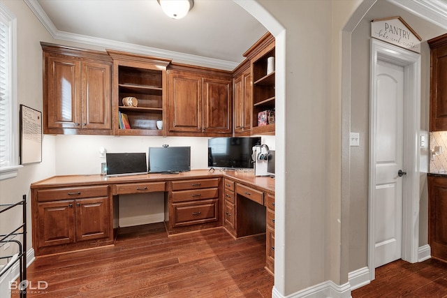 office area with dark wood-type flooring, built in desk, and ornamental molding