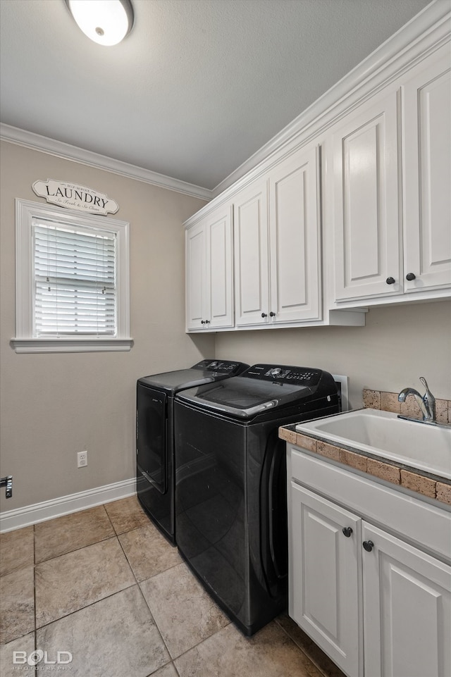 clothes washing area featuring cabinets, sink, washer and dryer, and crown molding