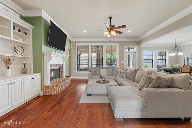 living room featuring a fireplace, ceiling fan with notable chandelier, dark hardwood / wood-style flooring, and ornamental molding