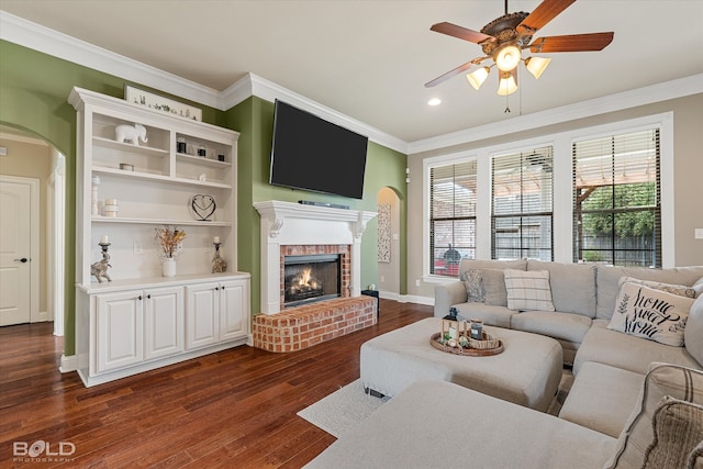 living room with a brick fireplace, dark hardwood / wood-style flooring, and ornamental molding