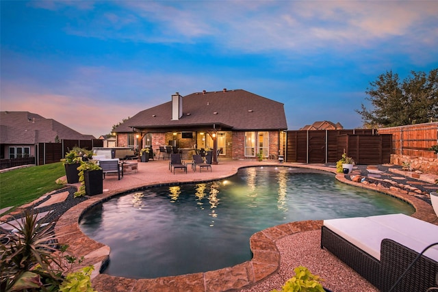 pool at dusk featuring a jacuzzi and a patio