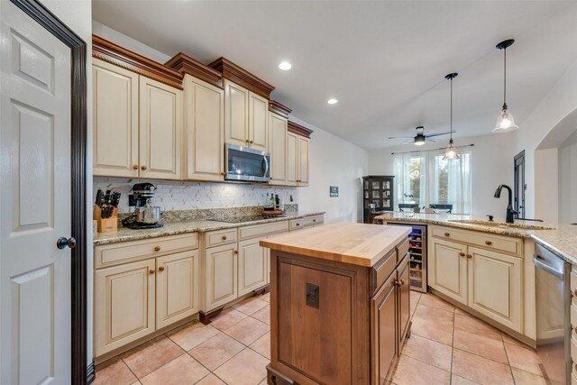 kitchen featuring a center island, butcher block counters, stainless steel appliances, wine cooler, and sink