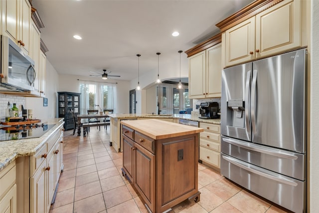 kitchen with wood counters, stainless steel appliances, tasteful backsplash, hanging light fixtures, and a center island