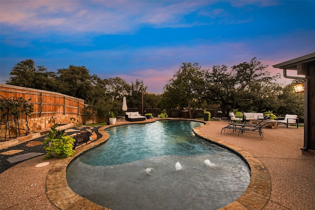 pool at dusk with a patio area, outdoor lounge area, and pool water feature