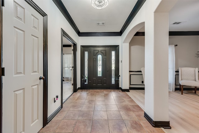 foyer with light tile patterned flooring and crown molding