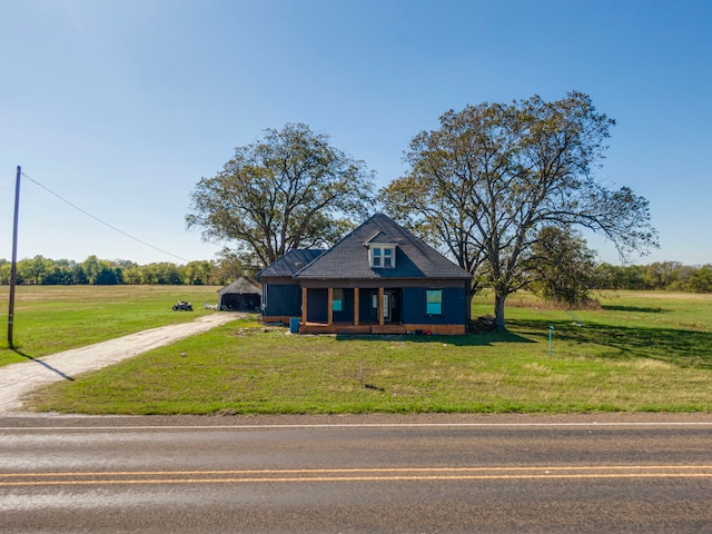 view of front facade featuring covered porch, a rural view, and a front yard