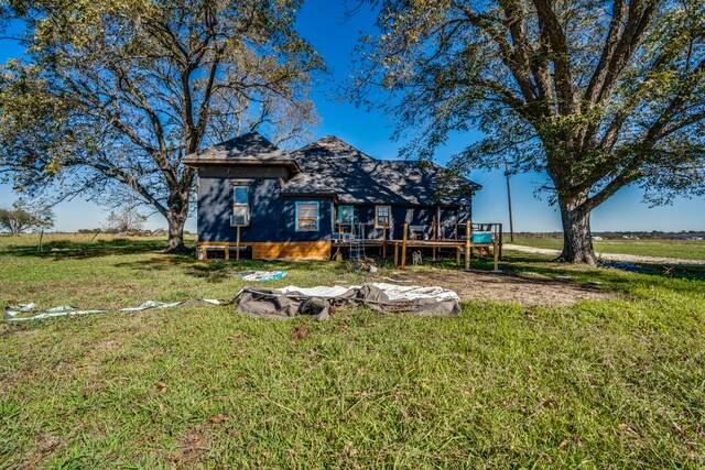 rear view of house featuring a wooden deck and a lawn