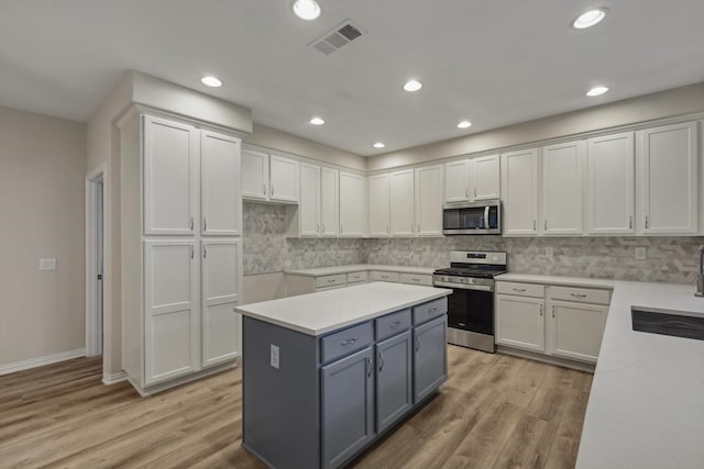 kitchen featuring white cabinets, gray cabinetry, stainless steel appliances, and light hardwood / wood-style flooring