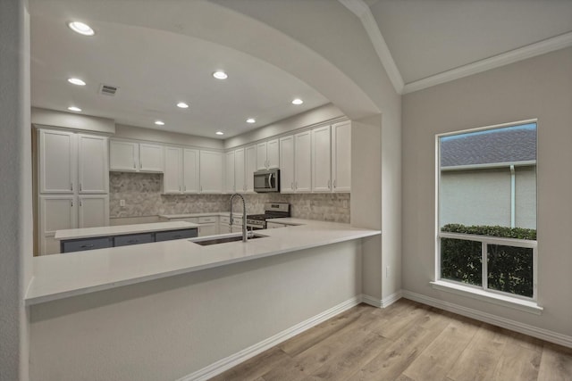 kitchen with backsplash, white cabinetry, light hardwood / wood-style flooring, and appliances with stainless steel finishes