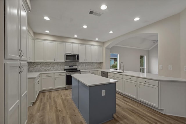 kitchen with kitchen peninsula, white cabinetry, sink, and appliances with stainless steel finishes