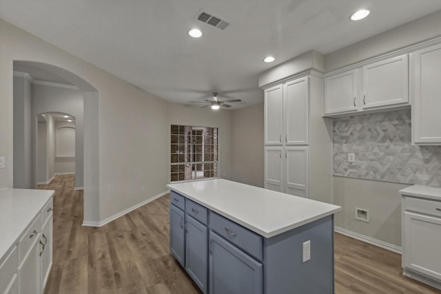 kitchen featuring tasteful backsplash, ceiling fan, hardwood / wood-style floors, a center island, and white cabinetry