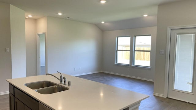 kitchen with lofted ceiling, a kitchen island with sink, sink, and hardwood / wood-style floors