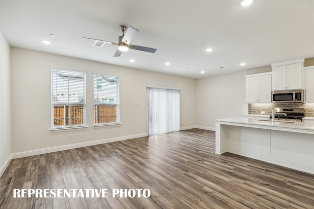 kitchen featuring white cabinetry, hardwood / wood-style flooring, backsplash, and appliances with stainless steel finishes