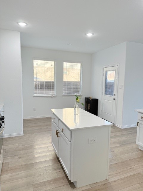 kitchen with white cabinets, a center island, and light hardwood / wood-style flooring