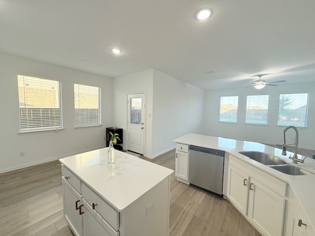 kitchen featuring sink, light hardwood / wood-style flooring, stainless steel dishwasher, a center island with sink, and white cabinets