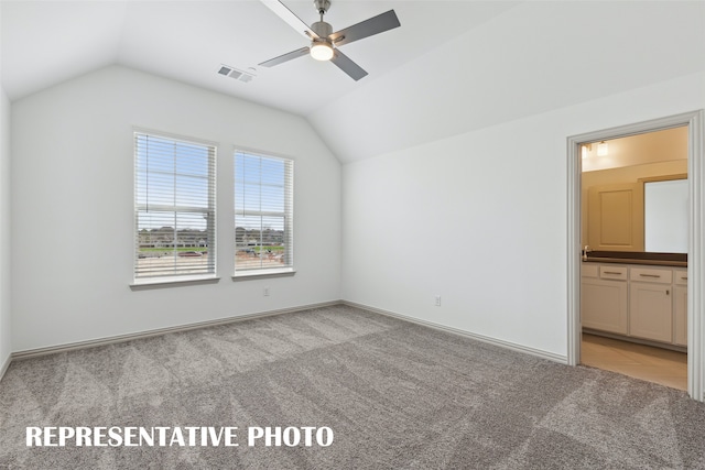 interior space featuring ensuite bath, ceiling fan, lofted ceiling, and light colored carpet