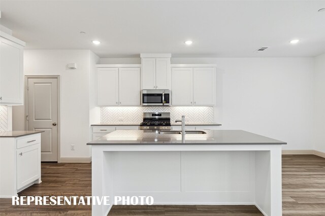 kitchen with white cabinetry, an island with sink, appliances with stainless steel finishes, and dark wood-type flooring