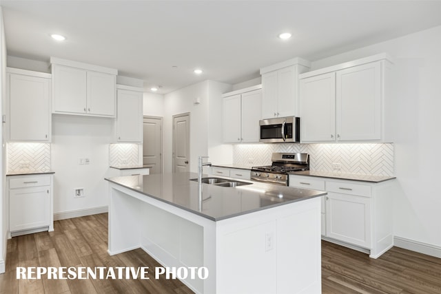 kitchen featuring dark hardwood / wood-style flooring, white cabinetry, an island with sink, and stainless steel appliances