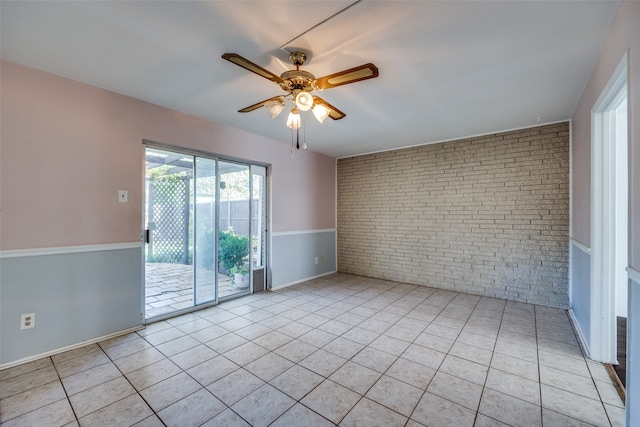 unfurnished room with brick wall, ceiling fan, and light tile patterned floors