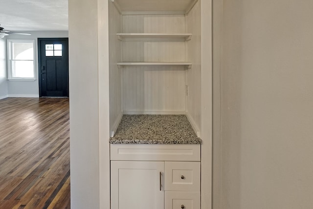 bar featuring light stone countertops, dark hardwood / wood-style flooring, white cabinetry, and ceiling fan