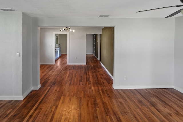 spare room featuring dark hardwood / wood-style flooring and ceiling fan with notable chandelier