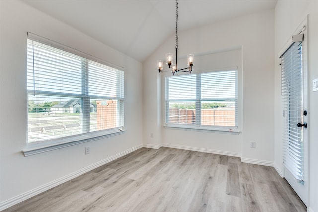 unfurnished dining area with a notable chandelier, lofted ceiling, and light hardwood / wood-style floors