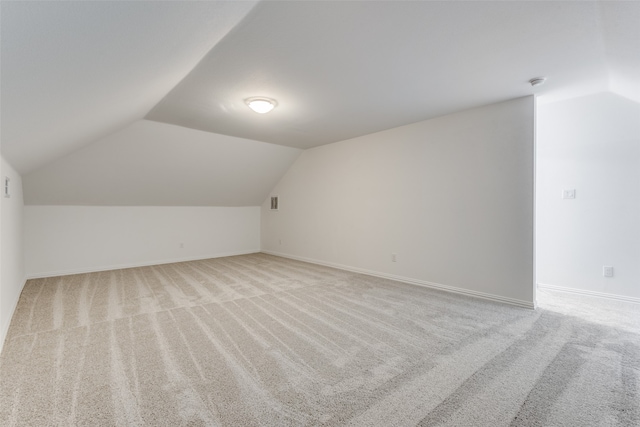 additional living space with light carpet and vaulted ceiling